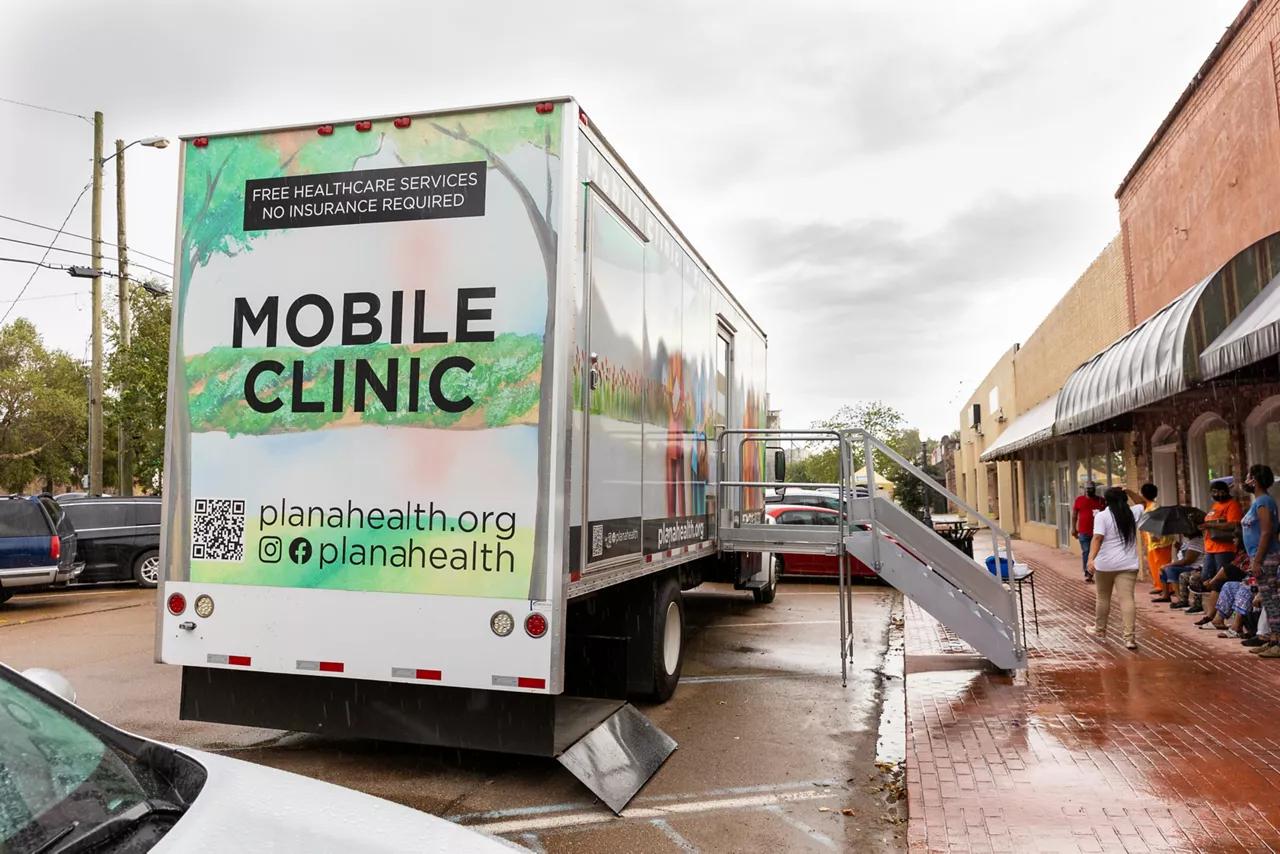 Mobile health clinic parked on a street with people waiting